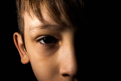 Close-up portrait of boy against black background