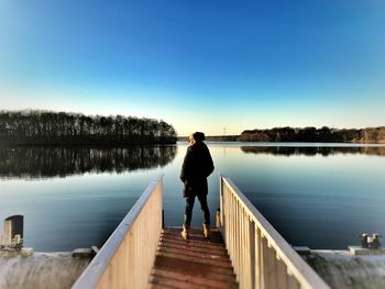 Rear view of woman standing on jetty