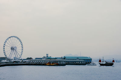 Hong kong observation wheel at victoria harbor against sky