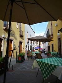 Chairs and tables at restaurant by buildings in city
