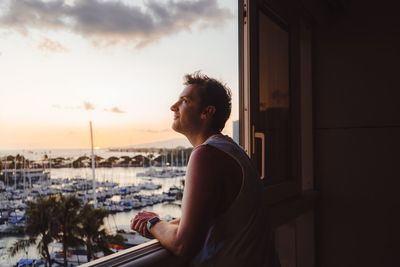 Man looking through window during sunset