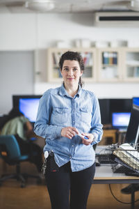 Portrait of confident mature female teacher standing in computer lab at high school