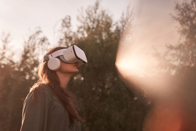 Teenage girl in vr helmet in the park on background of trees