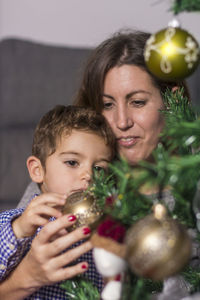 Mother and son decorating christmas tree at home