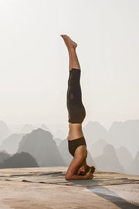 Beautiful woman practising yoga above the kast mountains of yangshuo