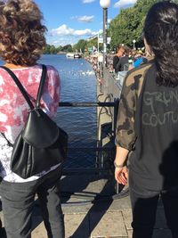 Rear view of man and woman standing on river against sky