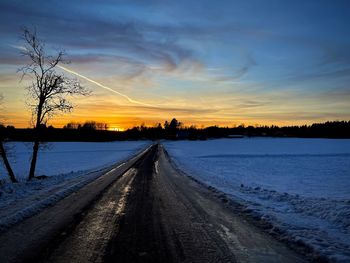 Road by lake against sky during sunset