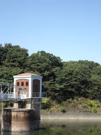 Built structure by trees against clear sky