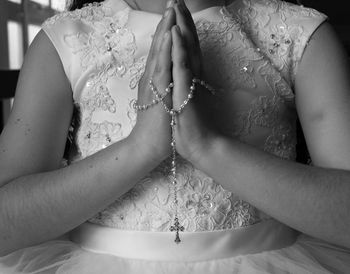 Midsection of girl holding rosary while praying