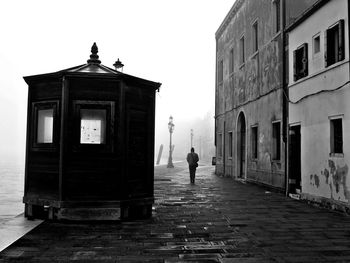 Man walking on road against buildings