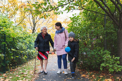 Full length of happy senior woman walking with daughter and great grandson in park