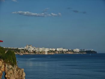 Sea by city buildings against sky