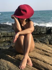 Woman sitting on beach against sea