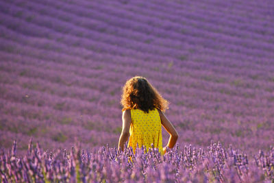 Rear view of woman walking on field