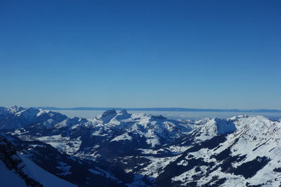 Scenic view of snowcapped mountains against clear blue sky