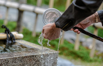 Cropped hand taking water with ladle at buddhist temple