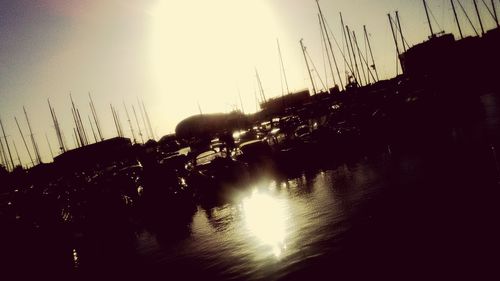 Silhouette boats moored at harbor against sky during sunset