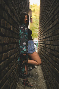 Young woman standing against brick wall