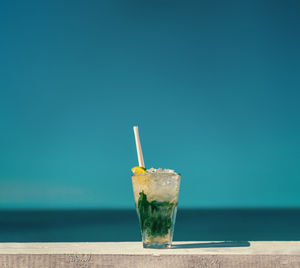 Mojito, served on a table infront of clear blue sky and the open sea.