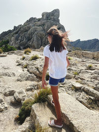 Woman standing on rock at beach against sky