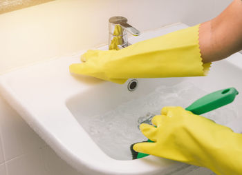 Close-up of person hand holding faucet at home