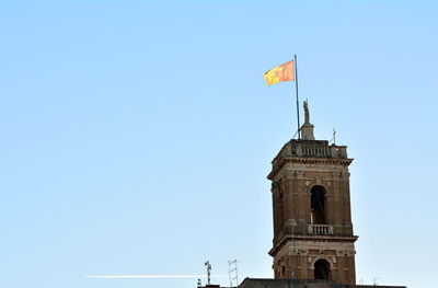 Low angle view of flag on building against clear blue sky