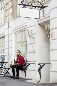 Owner having coffee while sitting outside candy store