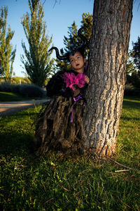 Portrait of woman on tree trunk in field