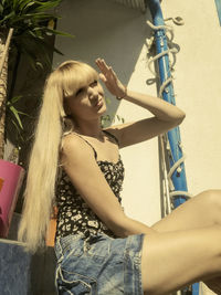 Low angle view of woman with long hair sitting against wall