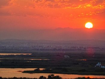 Scenic view of landscape against dramatic sky during sunset