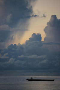 Silhouette sailboat in sea against sky during sunset