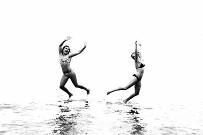 Full length of silhouette woman jumping on beach against sky