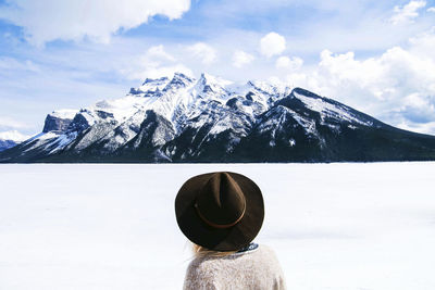 Rear view of woman in fedora hat looking at view against cloudy sky