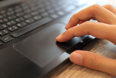 Cropped image of person using laptop on table