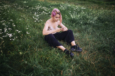 Girl with a phone sitting on a green meadow