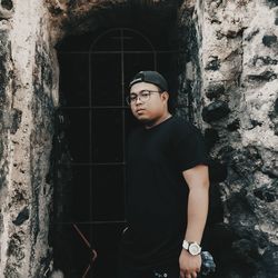 Young man standing against metallic window of old building