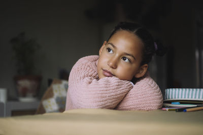 Girl resting head on arms and day dreaming at home
