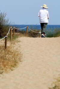 Rear view of man on beach against sky