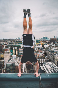 Rear view of man with arms outstretched against cityscape