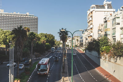 Cars on street by buildings in city against clear sky