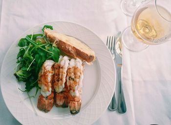 High angle view of seafood in plate by white wine on table