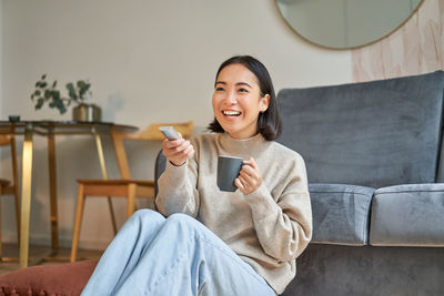 Portrait of young woman sitting on sofa at home