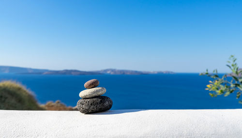 Close-up shot of pebbles stacked on each other in a balance with santorini caldera in the background