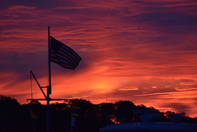 Silhouette flag against orange sky