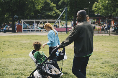 Family walking on grassy field at park