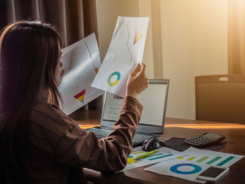 Businesswoman analyzing graphs at desk in office