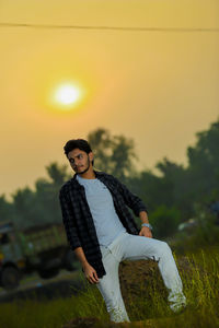Man standing on field against sky during sunset