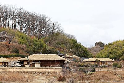 Houses and trees in village against sky