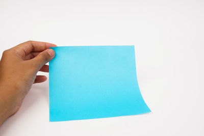 Close-up of hand holding paper against white background