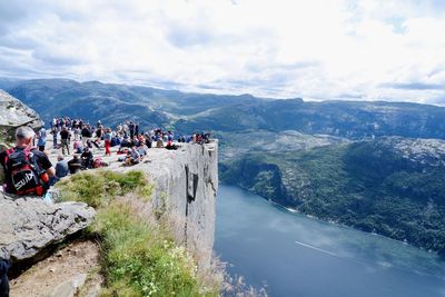 People looking at town by mountain against sky